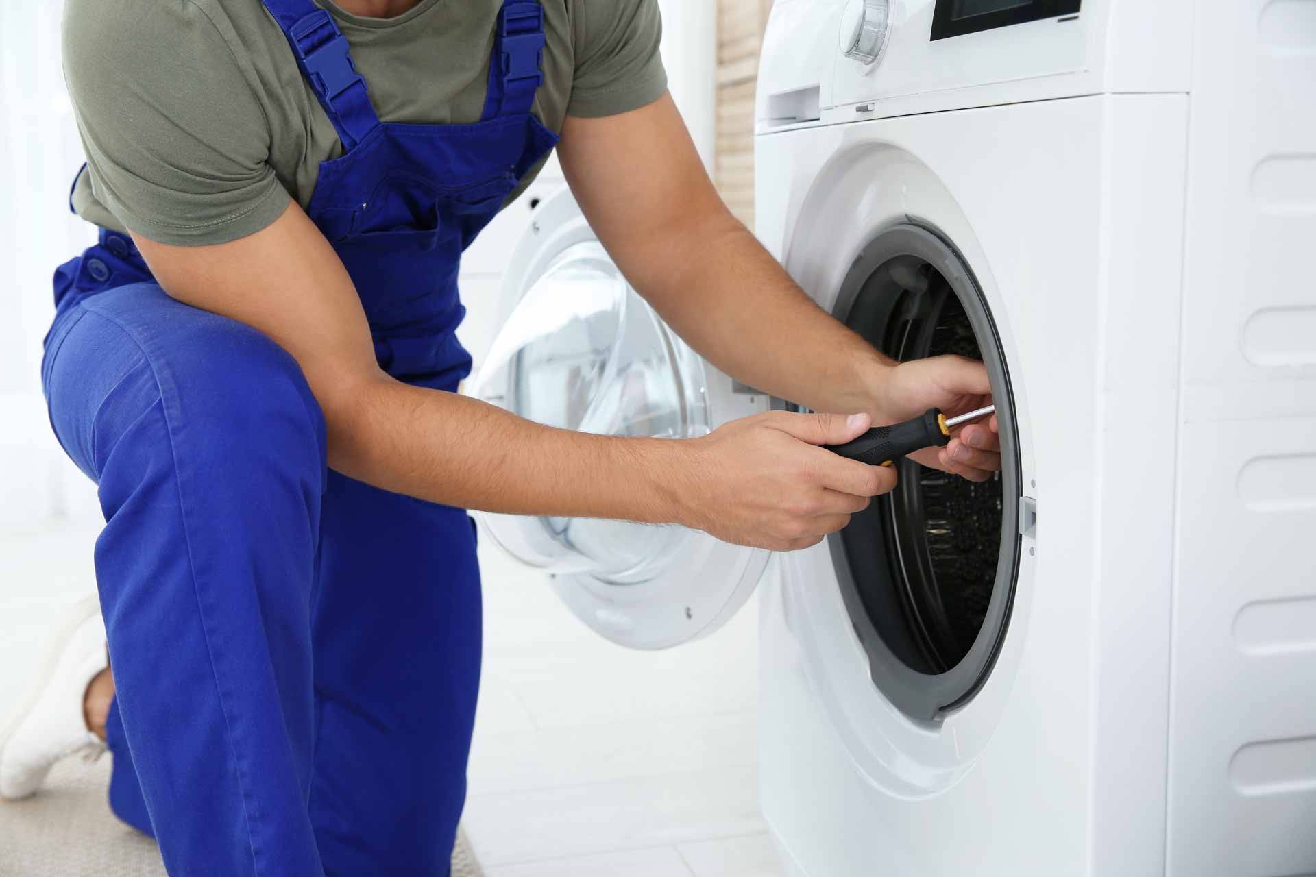 Technician kneeling to repair a washer/dryer