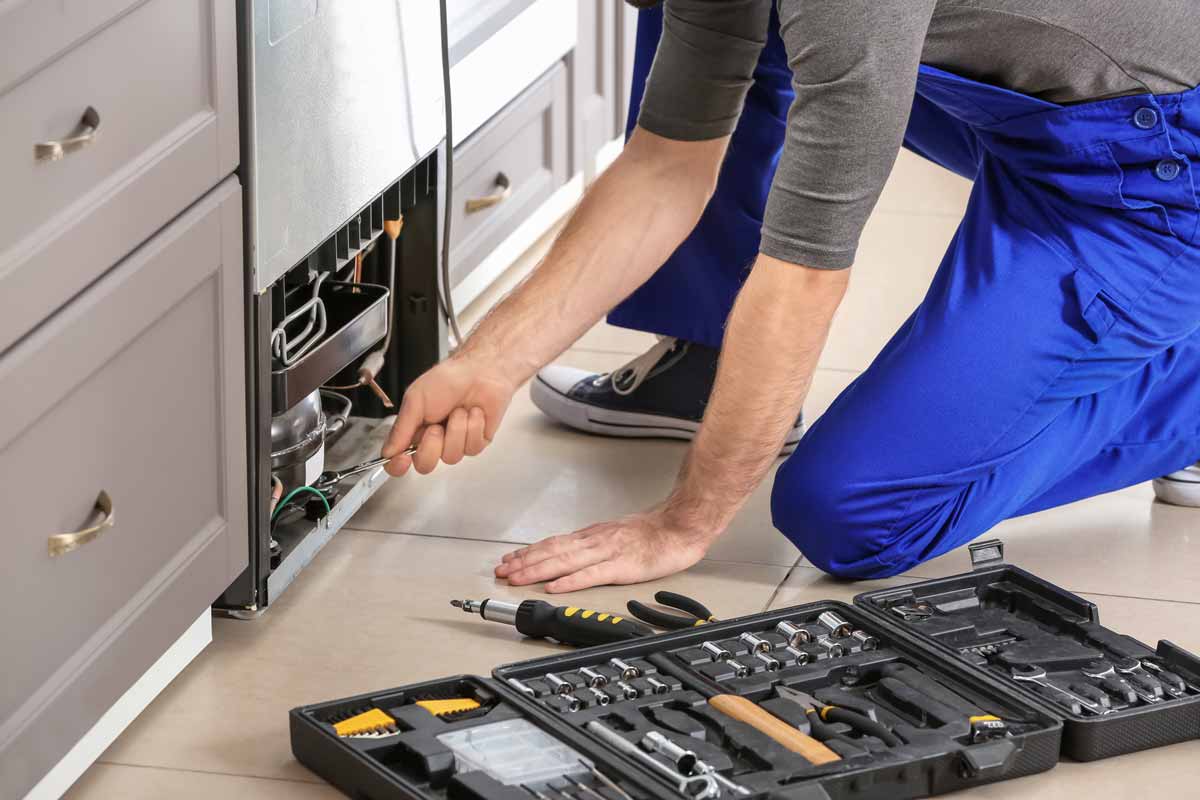 Technician repairing bottom panel on refrigerator