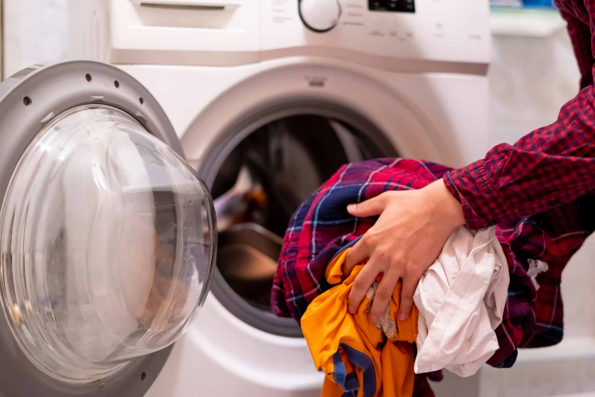 Homeowner loading wet laundry in to washer/dryer